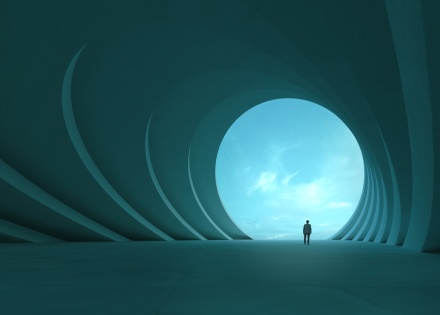 Man standing in a building looking out to the sky.
