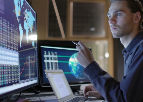Man analyzing market expansion across several monitors