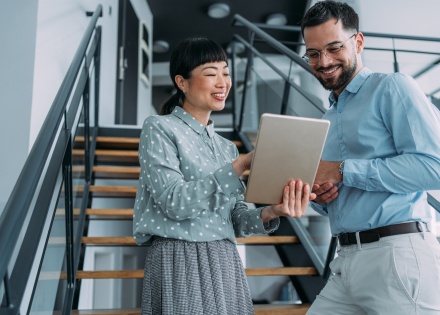 Two coworkers reading about small business employee benefits on a tablet