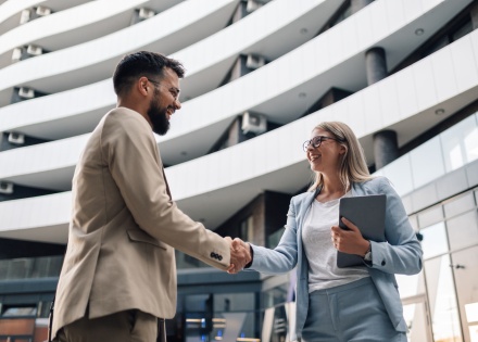 Business people in Dominica shaking hands in front of an office building