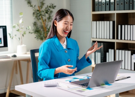 Businesswoman wearing a blue suit sits at her office desk in Laos