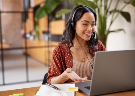 Woman smiling and working on a laptop during a video call