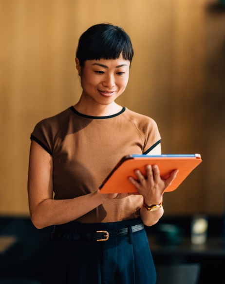 Professional woman walking and looking at EOR services on tablet.