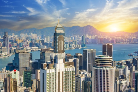 Aerial view of sunrise over Hong Kong's skyscrapers, bay, and mountains