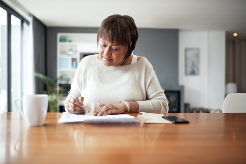 Mature woman at home working through payroll taxes in Jordan