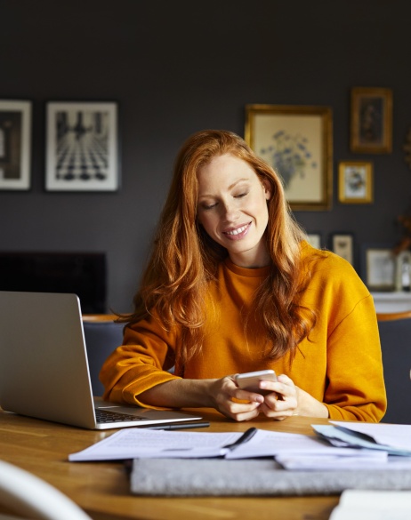 Female employer reviewing Pebl M&A services on laptop and phone while working from home.