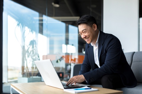 Smiling businessman working on a laptop in an office in South Korea