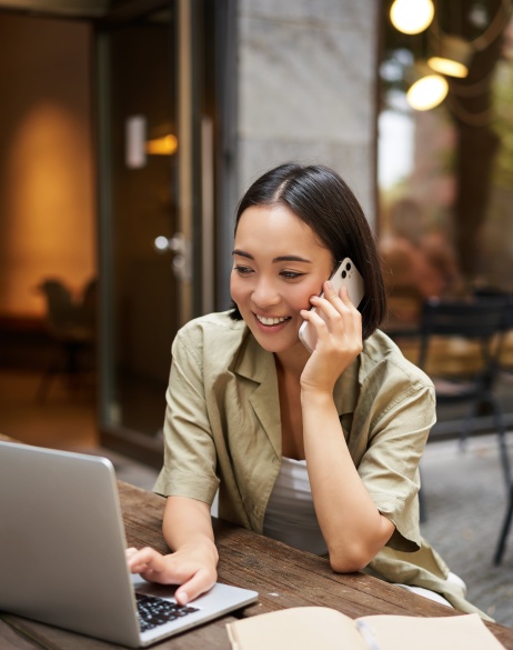 Woman on phone while looking at laptop of global hiring options with Pebl EOR.