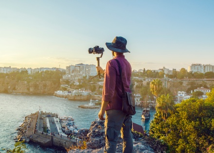 Hero image of a man with camera taking a photo of a coast line