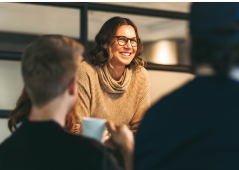 Focus on a woman in a room with others discussing global payroll best practices